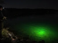 Angler using a green underwater fish light to attract fish while night fishing from the lakeshore